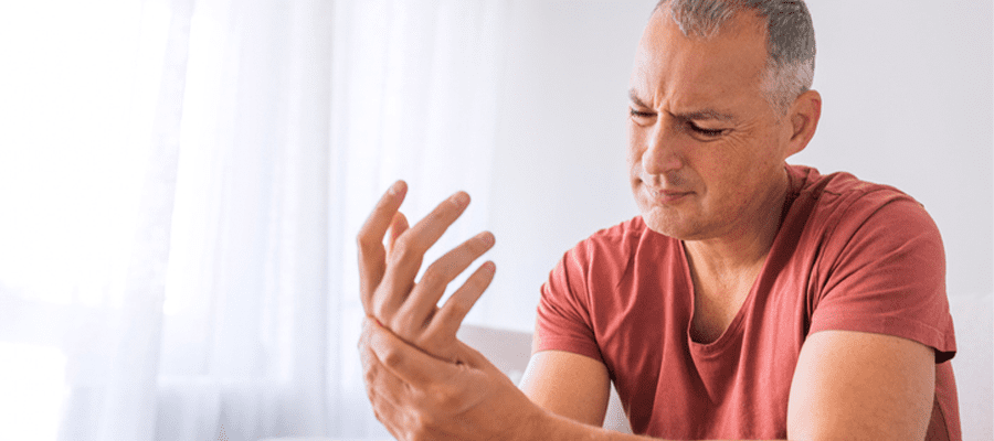 Man heeft last van pijn in de handen, veroorzaakt door reuma
